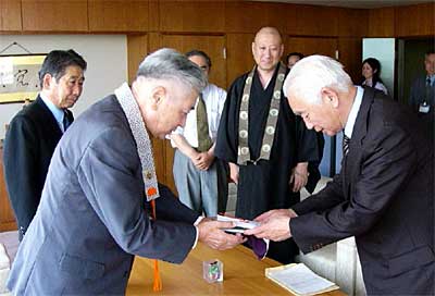 佐藤市長職務執行者(右)に善意を手渡す山崎三条組門徒総代会会長(左)