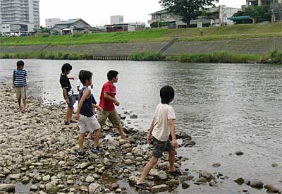 猛暑となった「海の日」の18日、五十嵐川河川敷で石きりをして遊ぶ子どもたち