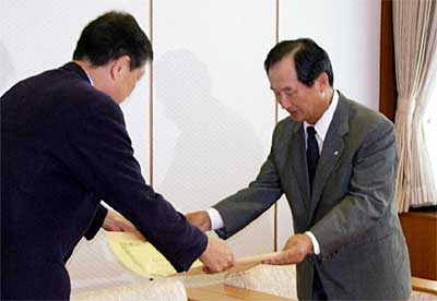 高橋三条市長(左)から紺綬褒章の褒状を受ける杉野三条信用金庫理事長(右)