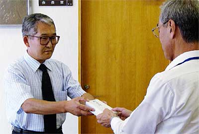 岩本三条市社会福祉協議会事務局長(右)に善意を手渡す佐野はし供養祭実行委員長