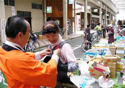 18日、燕市・サンロード宮町で行われた県共同募金会燕市支会の赤い羽根共同募金の街頭募金、市民の胸に赤い羽根をつける高橋燕市長