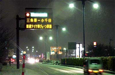 「三条燕－小千谷　普通タイヤ車チェーン装備」と表示する三条燕インターチェンジ入り口の道路情報案内板