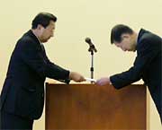 加藤角利産業(株)社長(左)からモチの目録を受け取る高橋三条市長(右）