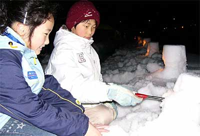 加茂川で行われた雪灯ろうに火をともす子どもたち