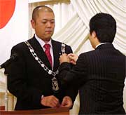 渡辺前理事長(右)から理事長バッジを受ける丸山新理事長(左)