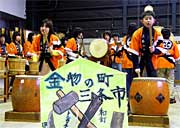 三条鍛冶道場に贈った六角凧を前に金物太鼓を演奏する児童