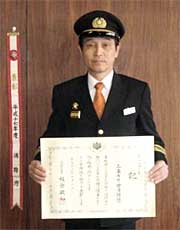 竿頭綬を横に、章記を手にする大橋三条市下田消防団長