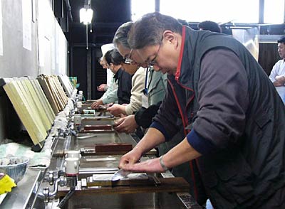 25日開かれた三条魚市場青年会の包丁研ぎ講習会で真剣な表情で砥石に向かう会員