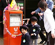 清掃後、ポストにレイをかける園児