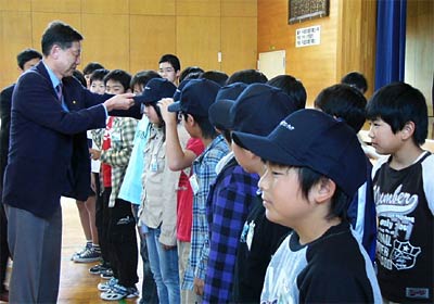 1日行われた三条市と森町小「笑っていい友21」の三条まち美化ボランティア調印式で高橋三条市長からボランティアの帽子をかぶせてもらう児童