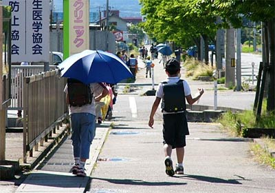 燕市内で雨傘を日傘代わりにして学校から帰る小学生