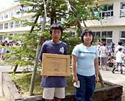 モミの木の前でメモリアルプレートをもつ青葉児童会委員長の古川くん(左)と環境委員会委員長の土肥さん(右)