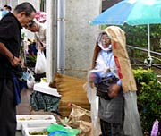 強い雨に紙袋やビニールをかぶってしのぐ出店者も