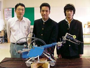 左から担当の住吉教諭、田辺君、岸本君と手前にロボット