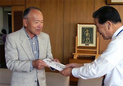 小林燕市長(右)に11万円を余りの善意を手渡すエムテートリマツの鳥部社長(左)