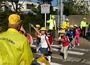 大崎小前の横断歩道を渡って下校する児童を見守る
