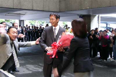 初登庁して市役所正面玄関前で支持者や職員の歓迎を受ける国定市長