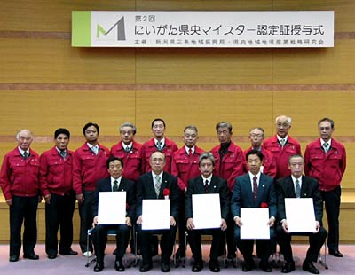 21日行われた第2回にいがた県央マイスター認定証書授与式で後列の赤いジャンパーを着た第1回の県央マイスターと並んで記念撮影する前列の認定証を手にした第2回県央マイスター