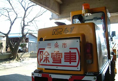 三条市厚生会館のひさしの下で待機する三条市の除雪車