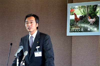 三条市の鳥、芝地鶏の写真パネルを背に会見する国定三条市長