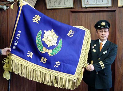表彰旗を広げる三条市栄消防団の桑原団長