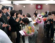 花束を手に職員の拍手に送られて退場する退職者