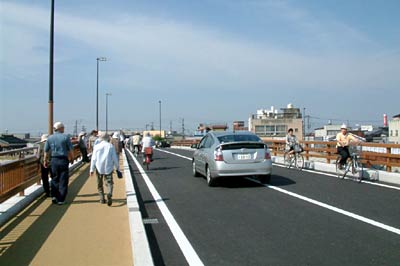 供用開始した一新橋の新橋を車や歩行者が次々と渡る