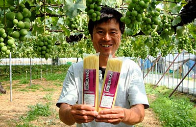 「ぶどう畑の謎麺」を手に渡辺果樹園の渡辺康弘さん