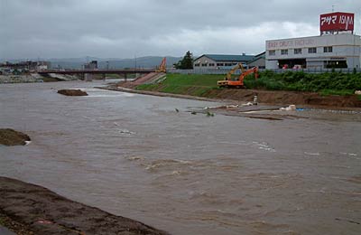昭栄大橋から上流方向の五十嵐川、赤い濁った水が流れる
