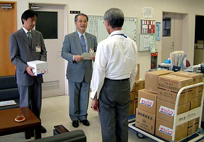 集まった使用済み切手を三条市社会福祉協議会の岩本事務鵜局長(右)に手渡す神野三条郵便局長(中央)と其部三条四日町郵便局長(左)キャプション