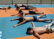 プールサイドで甲羅干しの中学生