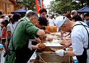 猛暑の中で焼きそばを調理して参拝者に無料配布