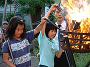 燃え盛る火の熱に顔をしかめてそろばんをくべる子どもたち