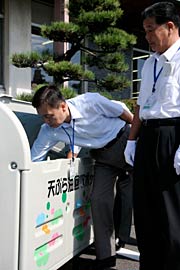 回収ボックスに第一号の廃油を入れる小林市長と中野副市長