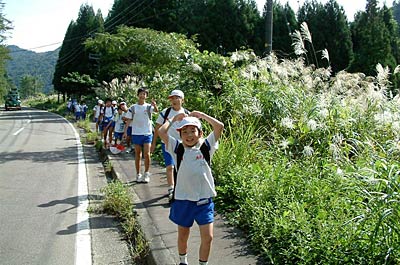 26日、「歩く遠足」で笠堀地内を「いい湯らてい」方向へ向けて歩く大浦小5、6年生