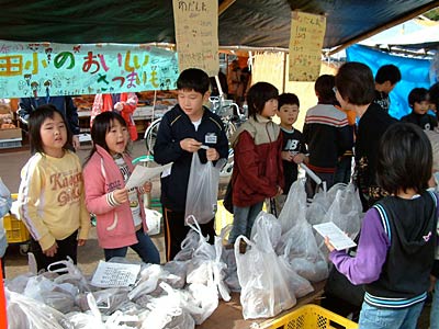 17日、二七の定期市で自分たちで栽培、収穫したサツマイモを売る飯田小3年生