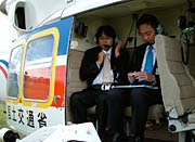 ヘッドホンとマイクを着けてヘリコプターに搭乗する国定三条市長