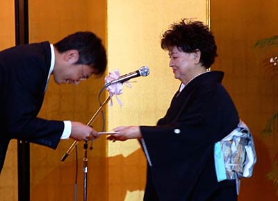 国定三条市長に100万円の寄付の目録を手渡すくらぶエッチの相田社長