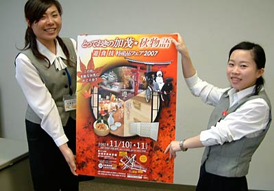 「とっておきの加茂・秋物語 遊食技 特産品フェア2007」のポスターを手にPRする加茂商工会議所職員