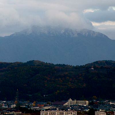 16日、三条市・パルム2屋上から紅葉の大崎山の向こうに初冠雪の粟ヶ岳