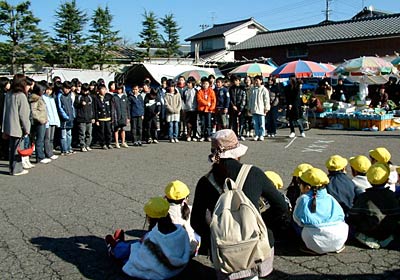 総合学習の一環で三条市・四日町市場で合唱ボランティアを行う四日町小6年生