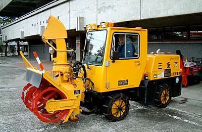 三条市厚生福祉会館駐車場で除雪出動に備えて歩道用の小型除雪機を点検する三条市職員