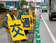「交通安全運動実施中」を一文字ずつ書いたボードを掲げてアピール