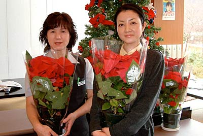 下田八木ヶ鼻温泉「いい湯らてい」が抽選でプレゼントするポインセチアの鉢植えを持つ職員