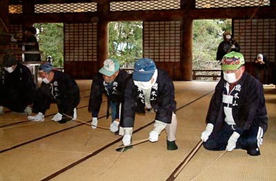 28日、三条市・本成寺で行われたすす払いで、本堂の畳をたたく門前信徒
