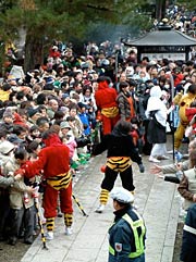 境内の参拝者の間を歩いて鐘楼堂へ向かう鬼たち