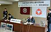 三条市旗と三條機械製作所の社旗を背に調印