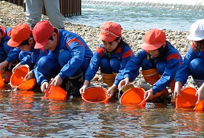 18日に五十嵐川の渡瀬橋上流右岸で行われた五十嵐川筋災害復旧事業安全対策協議会主催の飯田小4年生によるサケの稚魚の放流