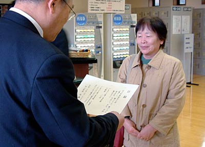 「ごまどう湯っ多里館」の入館者150万人目で佐藤田上町長から目録を受け取る稲垣さん