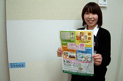 リホーム祭で実演する壁紙の前でちらしを手に来場を呼びかけるハンズワタベ社員